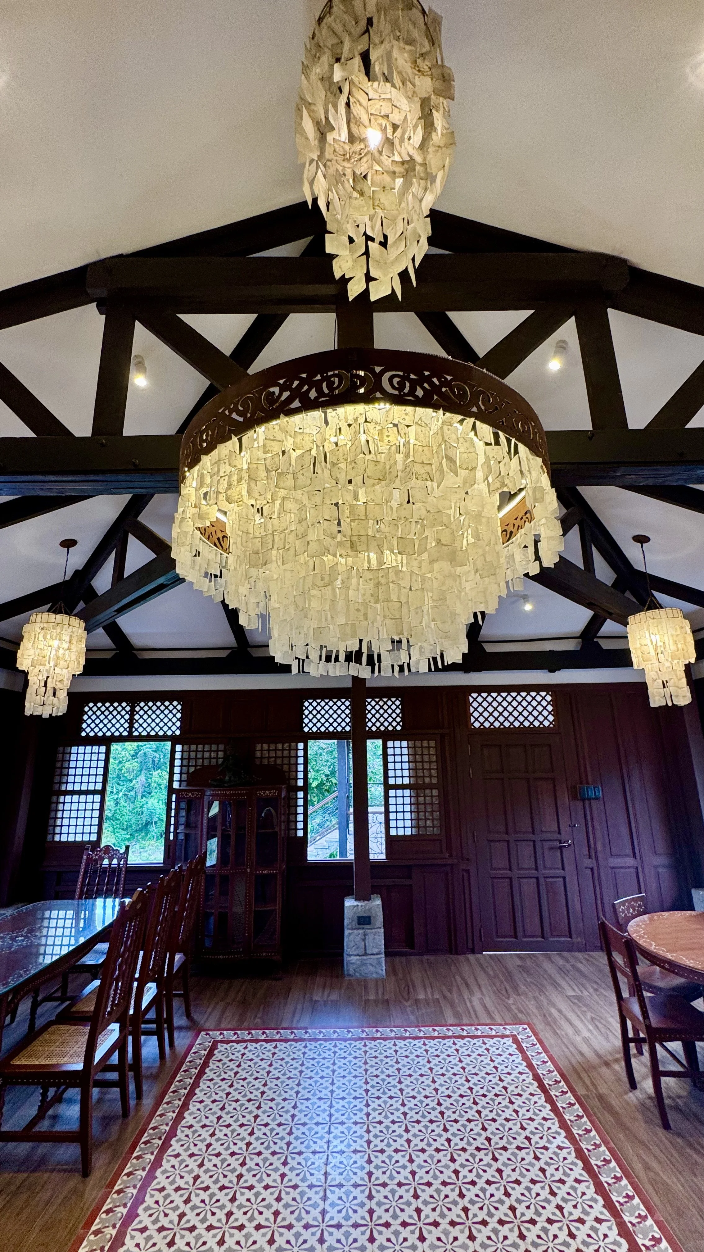 A capiz shell chandelier glowing warmly against dark hardwood trusses