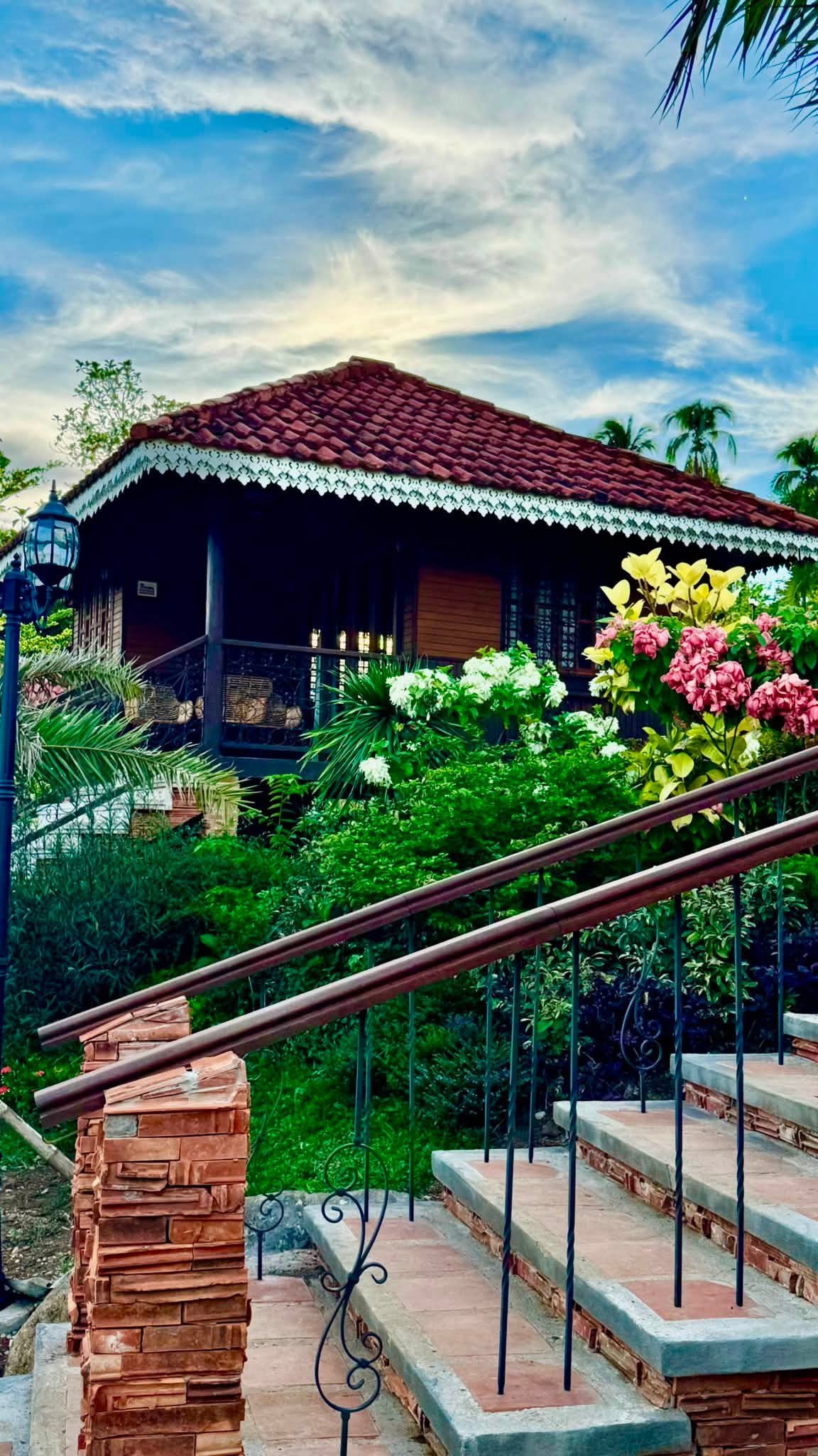 Garden stairway with wrought-iron rails and patterned tiles descending toward the cottages and river